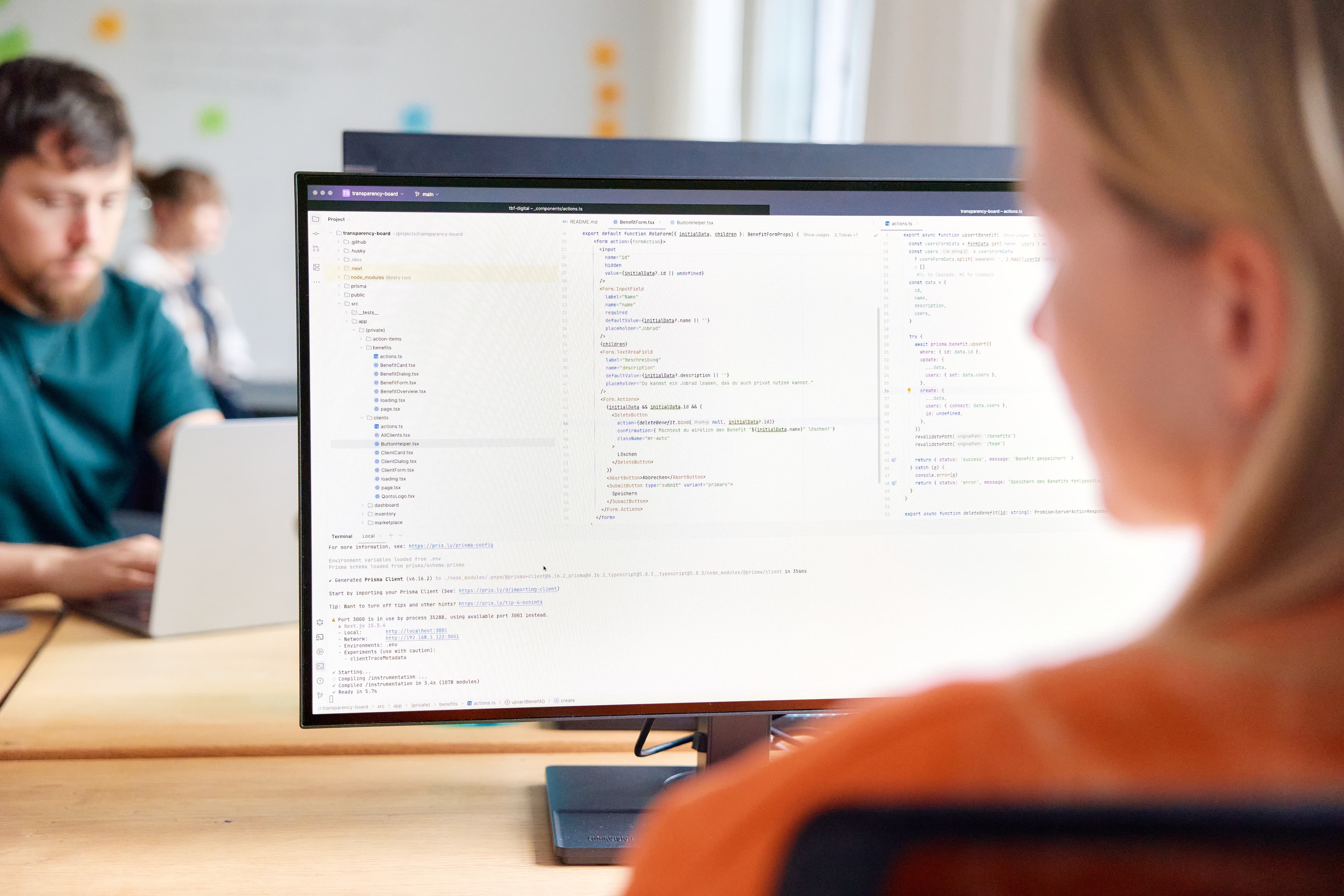 Software Developer infront of large screen showing code.